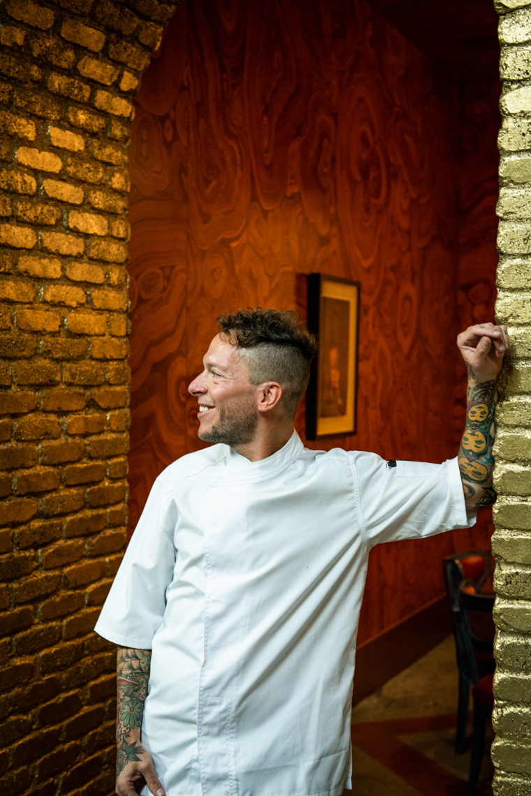Portrait of smiling chef in brick archway leaning against wall