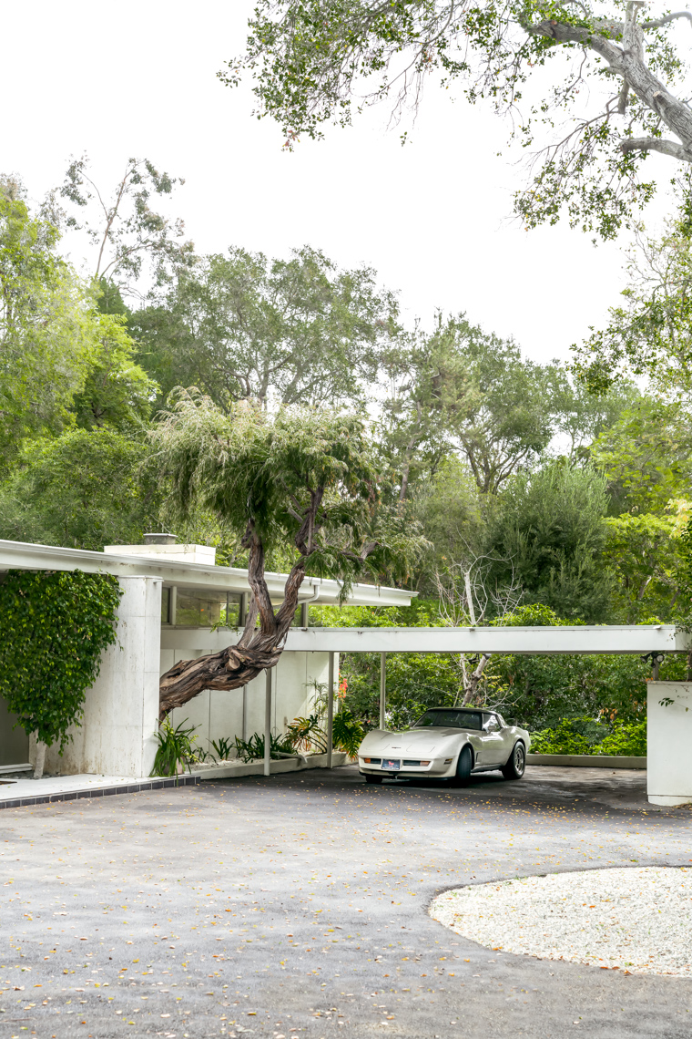 a vintage white corvette in the driveway of a mid century beverly hills home.
