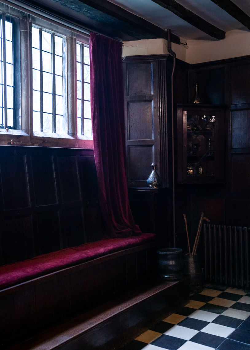Red velvet curtains and bench in dark room with white and black checkered floor