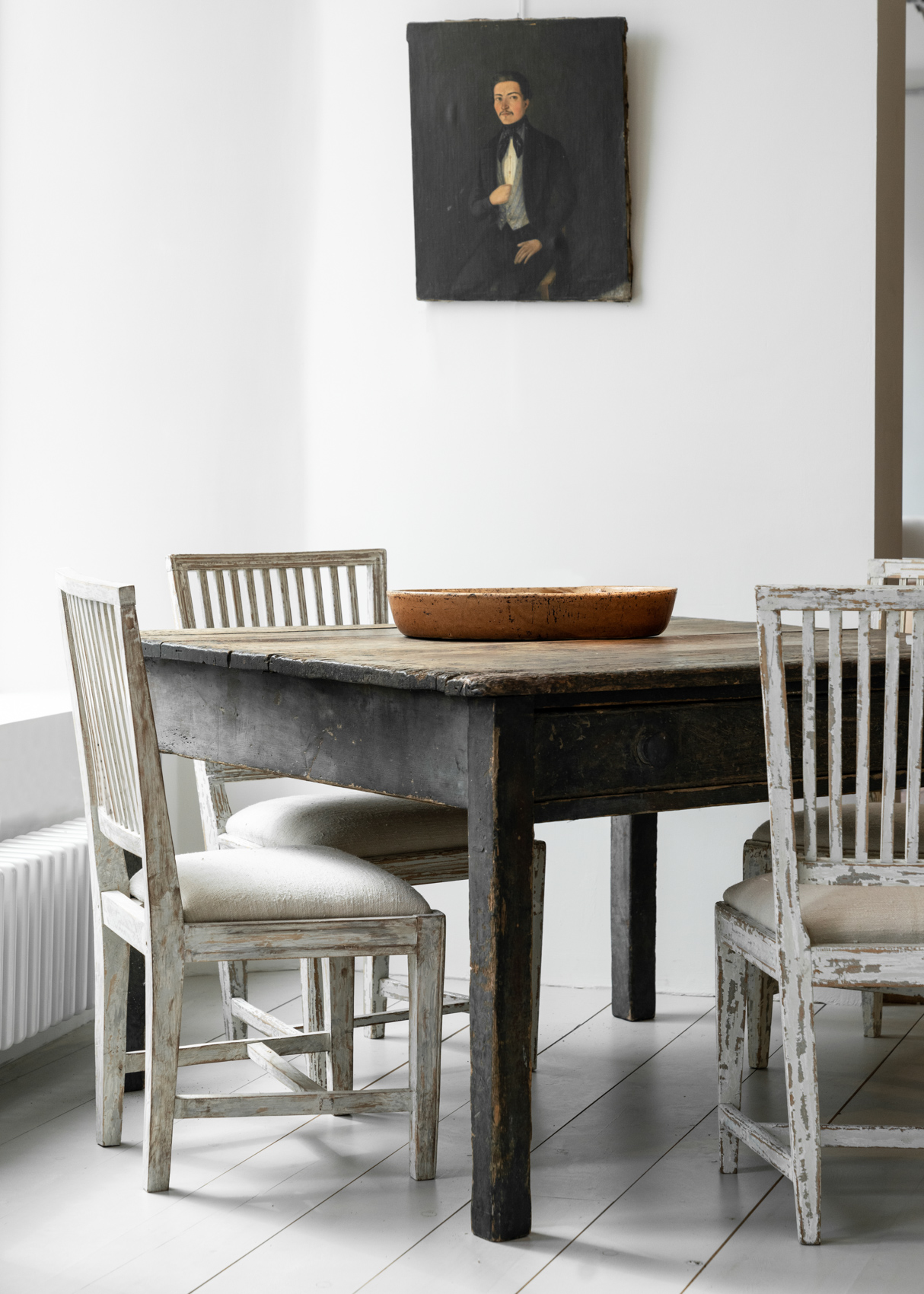 Antique french table and chairs under portrait of older gentleman