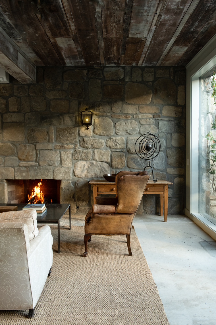 old leather chair by fireplace in stone wall living room
