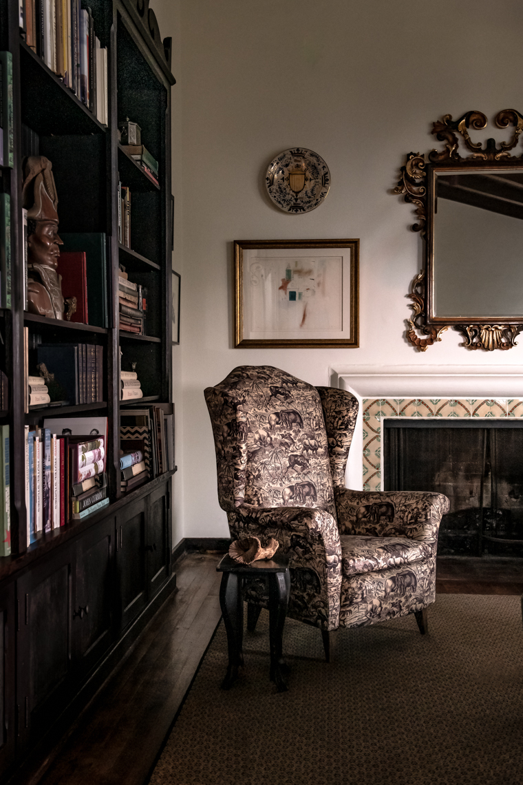 Blush and black printed chair in formal home library next to unlit fireplace